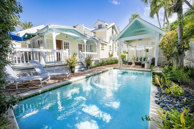 rear view of property with an outdoor pool and an outdoor living space