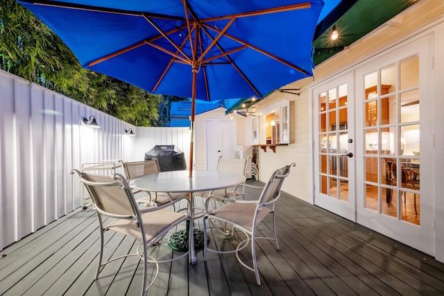 wooden deck with a storage shed, an outbuilding, fence, outdoor dining area, and french doors