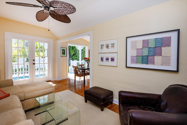 living area featuring ceiling fan, wood finished floors, baseboards, vaulted ceiling, and french doors