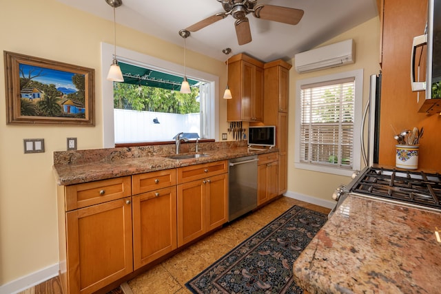 kitchen with stone counters, appliances with stainless steel finishes, brown cabinetry, an AC wall unit, and a sink