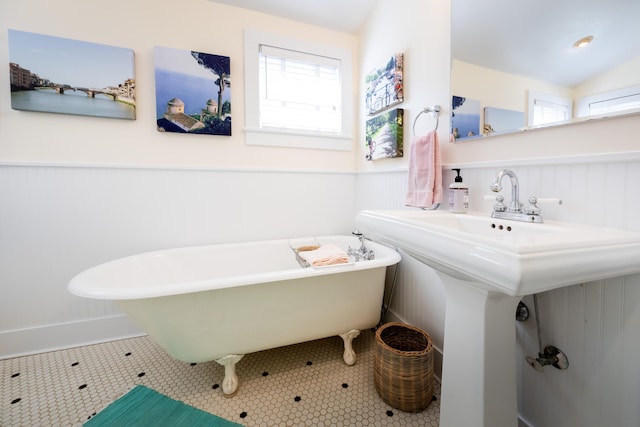 bathroom with a wainscoted wall, plenty of natural light, a freestanding tub, and lofted ceiling