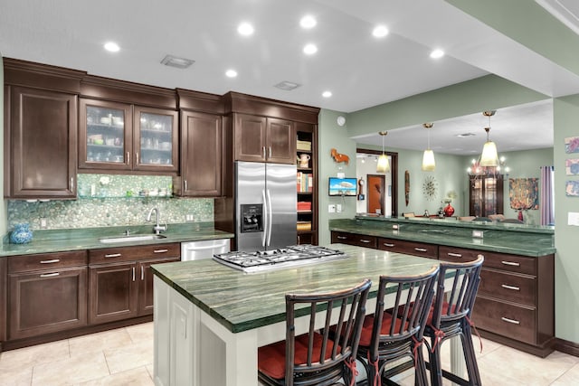 kitchen featuring decorative light fixtures, sink, a breakfast bar area, a center island, and stainless steel appliances