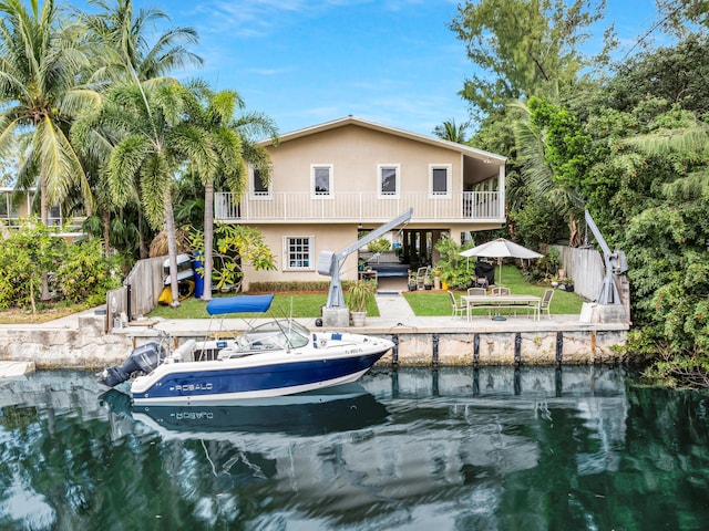 rear view of house featuring a water view, a balcony, and a lawn