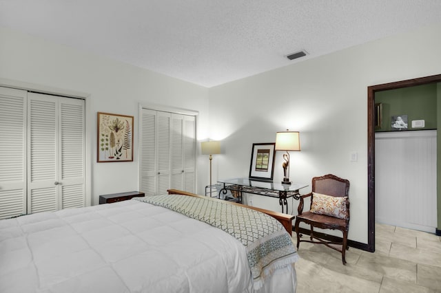 bedroom featuring two closets and a textured ceiling