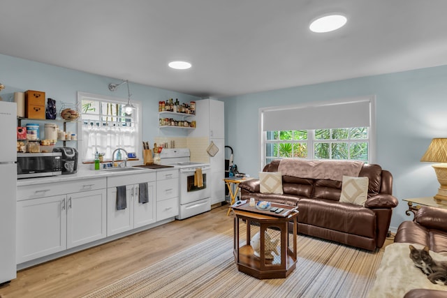 interior space featuring a healthy amount of sunlight, sink, white appliances, and white cabinets