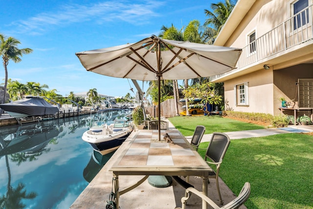 dock area featuring a water view, a balcony, and a lawn