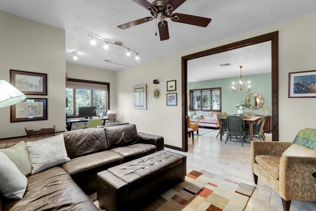 tiled living room with ceiling fan with notable chandelier and a textured ceiling