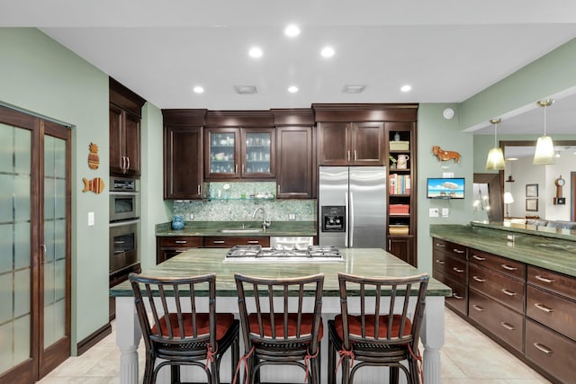 kitchen featuring a breakfast bar, sink, decorative backsplash, dark brown cabinetry, and stainless steel appliances