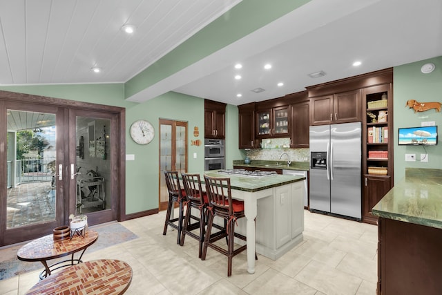 kitchen with sink, appliances with stainless steel finishes, a center island, vaulted ceiling, and french doors