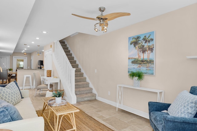 living area with stairway, baseboards, recessed lighting, ceiling fan, and light stone finish floors