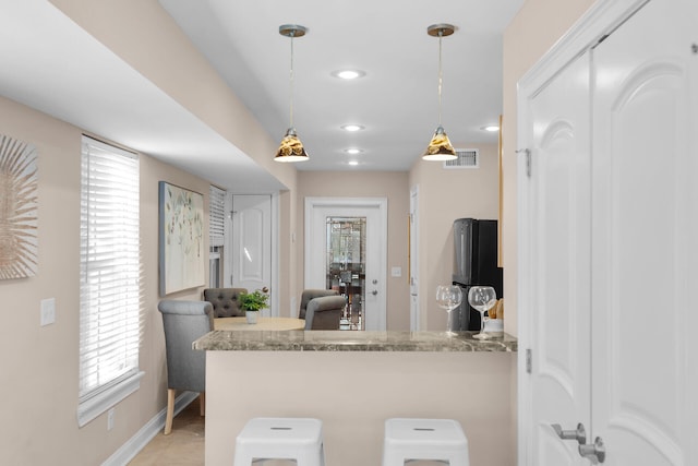 kitchen featuring refrigerator, a peninsula, light stone countertops, pendant lighting, and recessed lighting