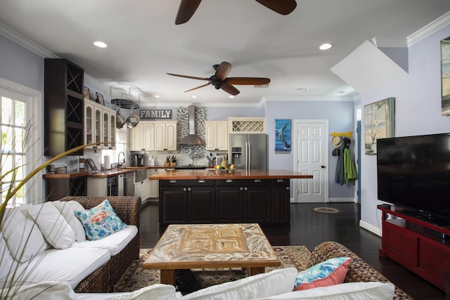 living room with dark hardwood / wood-style flooring, sink, crown molding, and ceiling fan