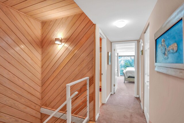 hall with carpet floors and wood walls