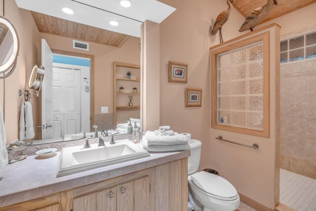 bathroom with vanity, toilet, and a tile shower