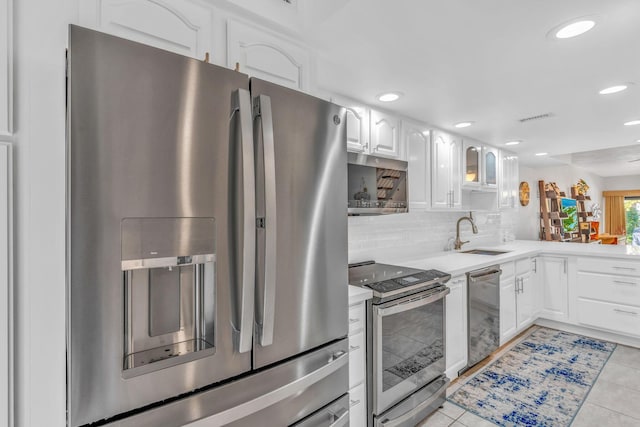 kitchen with stainless steel appliances, white cabinetry, sink, and light tile patterned floors