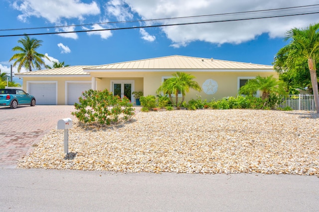 20771 W 2nd Ave, Cudjoe, FL 33042 - ranch-style home featuring a standing seam roof, stucco siding, an attached garage, driveway, and a metal roof
