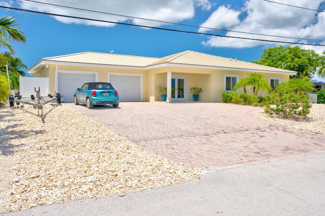 20771 W 2nd Ave, Cudjoe, FL 33042 - ranch-style home with decorative driveway, a garage, stucco siding, and a metal roof