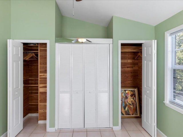 unfurnished bedroom with lofted ceiling, a closet, ceiling fan, and light tile patterned flooring