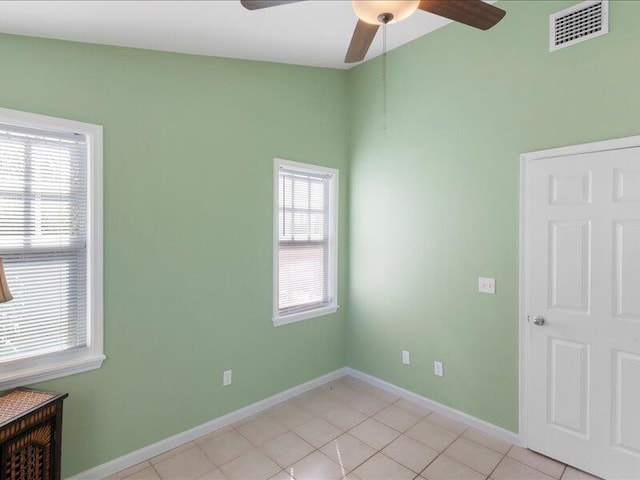 tiled empty room with a wealth of natural light and ceiling fan