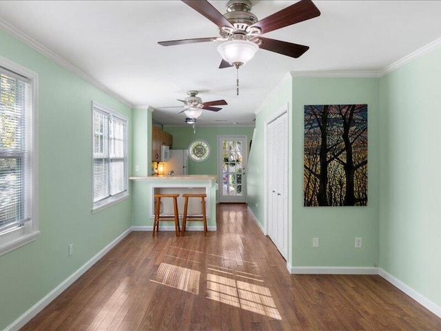 unfurnished living room with ceiling fan, ornamental molding, and dark hardwood / wood-style flooring