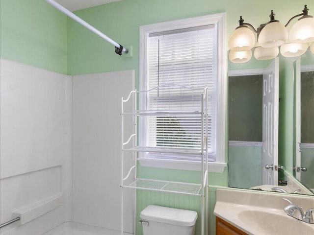 bathroom featuring walk in shower, a healthy amount of sunlight, toilet, and vanity