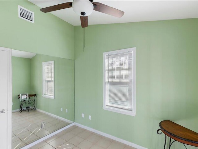 spare room with lofted ceiling, a wealth of natural light, ceiling fan, and light tile patterned floors