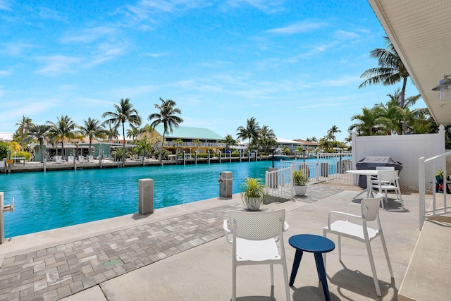 view of swimming pool featuring fence, a water view, and a patio area