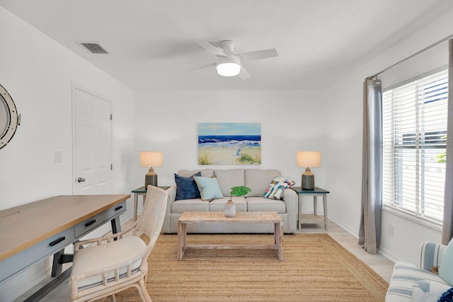 living room with ceiling fan, baseboards, and visible vents