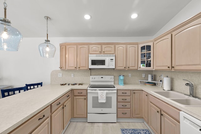 kitchen with backsplash, light brown cabinetry, a sink, and white appliances