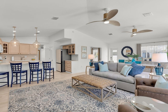 living room with lofted ceiling, visible vents, light wood-style flooring, and ceiling fan
