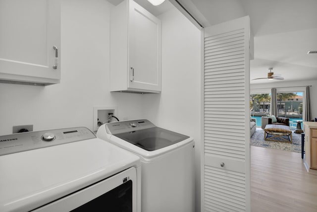 clothes washing area with washer and clothes dryer, visible vents, a ceiling fan, light wood-type flooring, and cabinet space