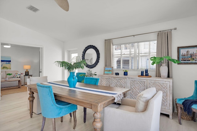 dining space featuring a wealth of natural light, lofted ceiling, visible vents, and light wood-style flooring