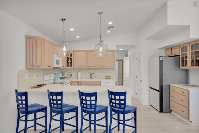 kitchen with a peninsula, white appliances, and light brown cabinetry