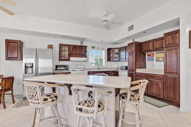 kitchen featuring light tile patterned flooring, ceiling fan, white electric stove, and a kitchen breakfast bar