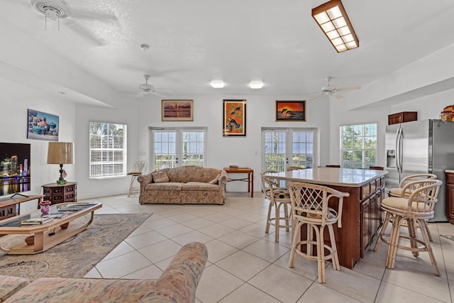 interior space with light tile patterned flooring, a kitchen island, stainless steel fridge with ice dispenser, and french doors