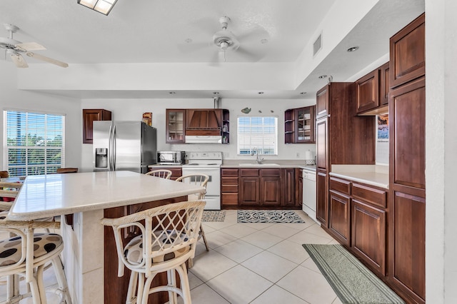 kitchen featuring a kitchen bar, sink, light tile patterned floors, appliances with stainless steel finishes, and ceiling fan