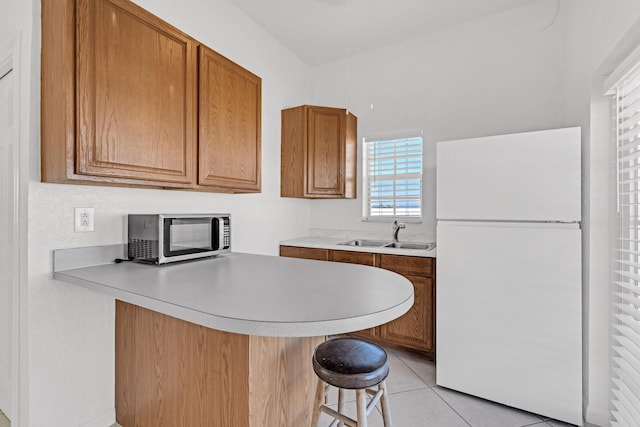 kitchen featuring sink, a kitchen breakfast bar, kitchen peninsula, and white fridge