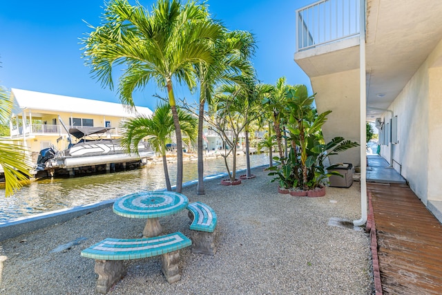 exterior space with a boat dock, a balcony, and a water view