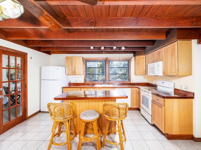 kitchen featuring a center island, white appliances, light tile patterned floors, and a sink