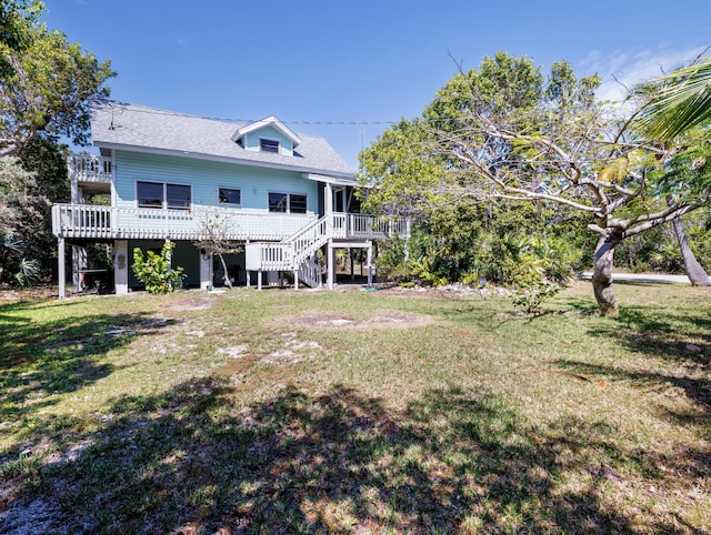 rear view of house featuring a deck, a shingled roof, stairs, and a yard