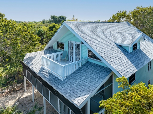 back of property with french doors and a shingled roof