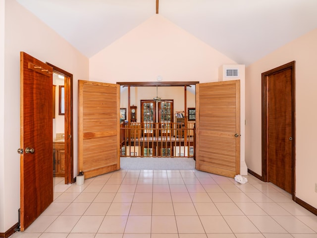 spare room with light tile patterned flooring, baseboards, visible vents, and high vaulted ceiling