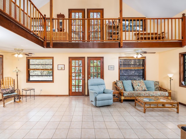 tiled living room with a high ceiling, baseboards, and ceiling fan