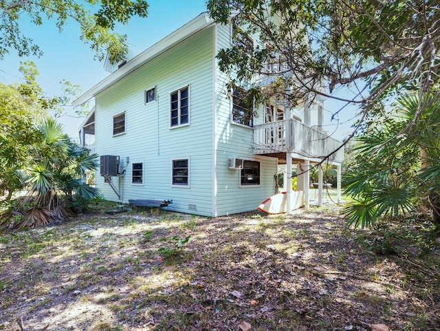 back of property featuring a wall mounted air conditioner and central AC unit