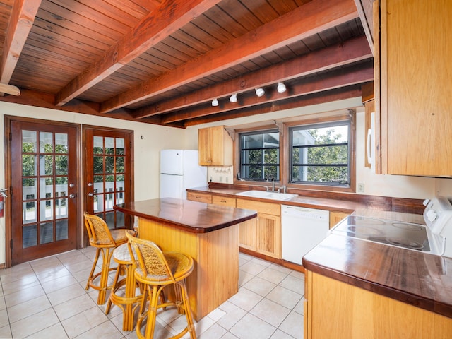 kitchen featuring a breakfast bar, a sink, french doors, white appliances, and light tile patterned floors