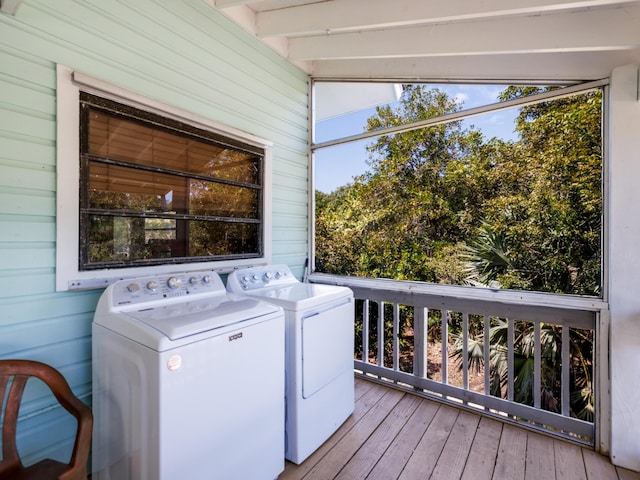 laundry area with washing machine and clothes dryer, laundry area, wooden walls, and hardwood / wood-style floors