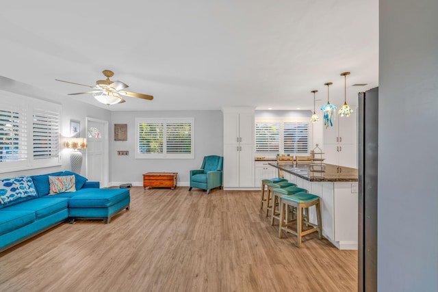 living room with a ceiling fan, baseboards, a healthy amount of sunlight, and light wood finished floors