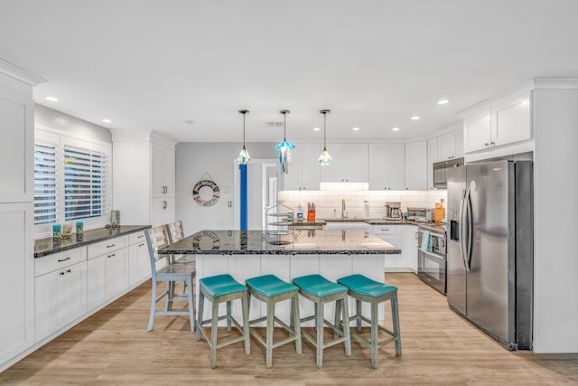 kitchen featuring backsplash, light wood-style flooring, stainless steel appliances, white cabinetry, and a sink