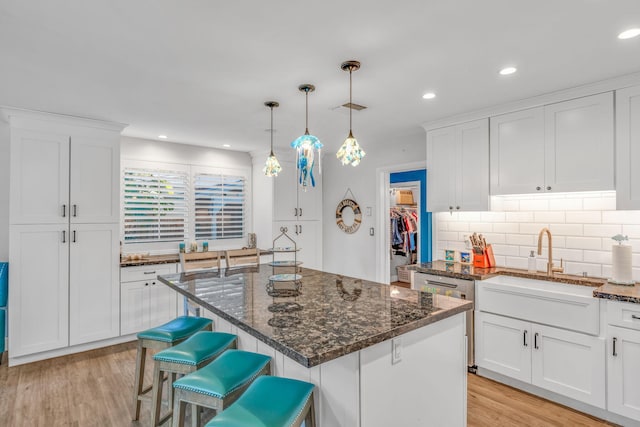 kitchen featuring tasteful backsplash, white cabinets, a sink, and light wood finished floors