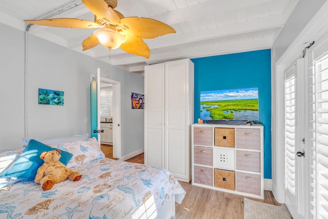 bedroom with beam ceiling, a closet, light wood-style flooring, ceiling fan, and baseboards